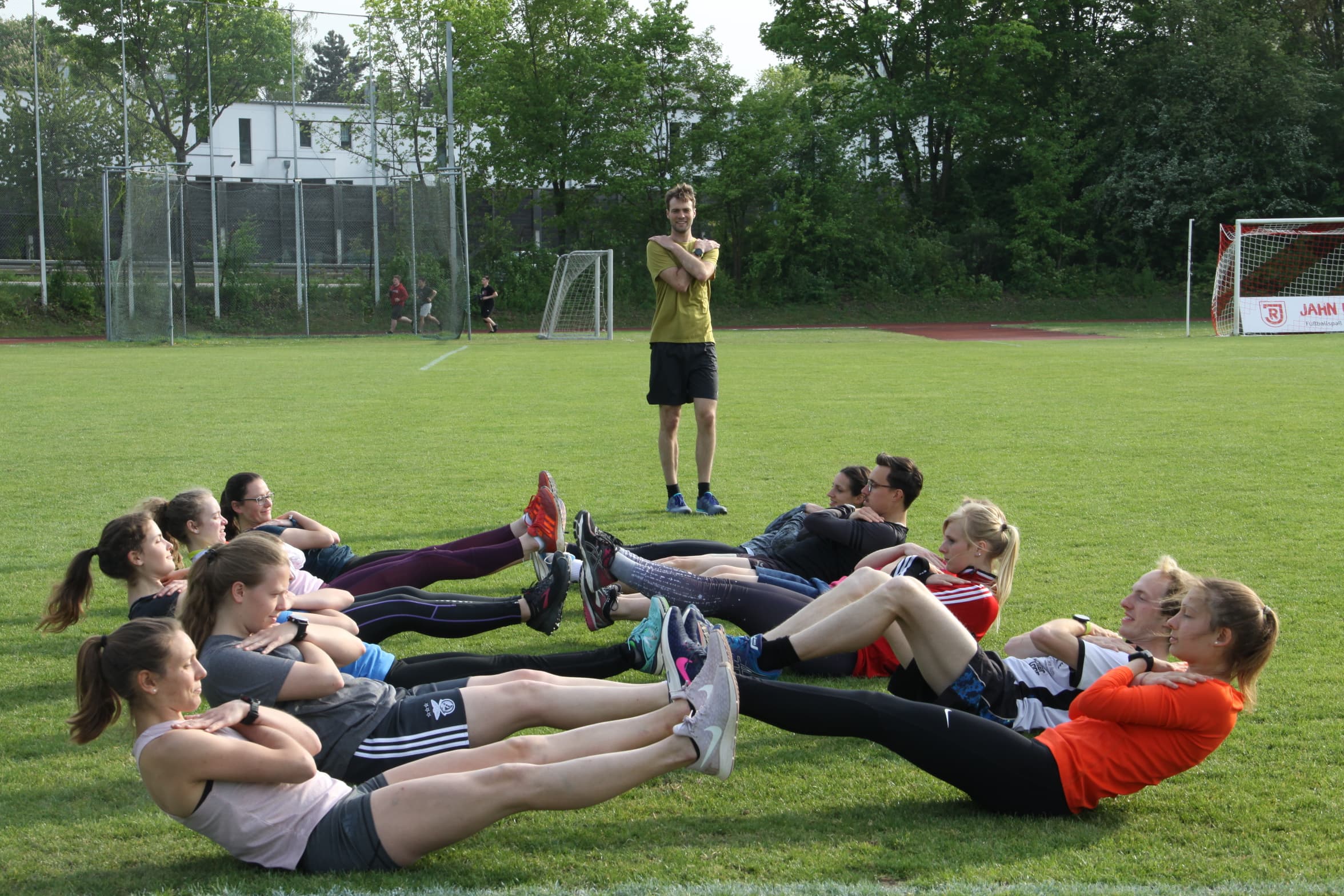 Laufgruppe beim gemeinsamen Athletiktraining auf dem Sportplatz