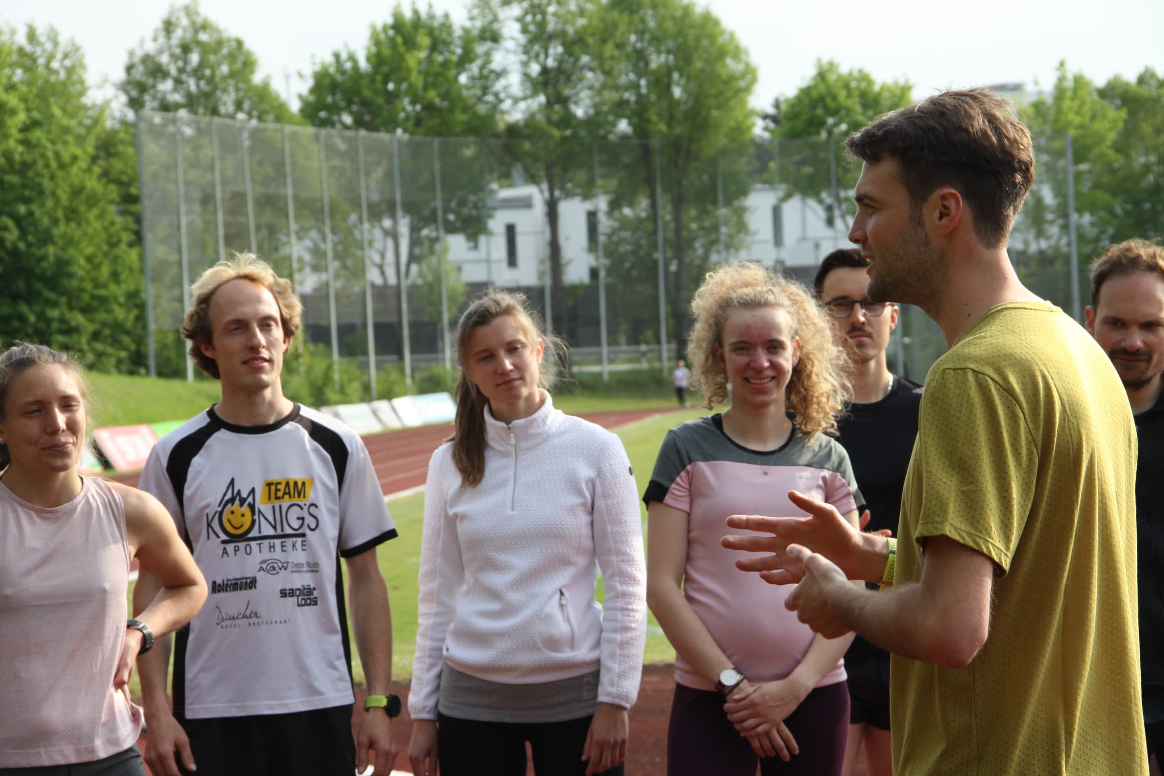 Trainer bespricht das Training mit seiner Laufgruppe an der Bahn